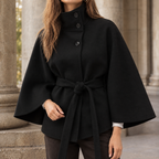 Woman wearing the belted cape coat in black with an asymmetric stand collar