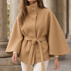 Woman wearing the belted cape coat in camel with an adjustable waist tie