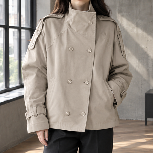 Woman wearing a khaki double breasted jacket with a stand collar and shoulder epaulettes