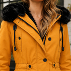 Close view of a gold hooded parka coat showing plush hood trim, drawstrings and a buttoned front.
