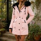 A woman wears a pink hooded parka coat with plush hood trim, front buttons and waist tabs.
