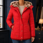 A woman wears a red hooded puffer jacket with a plush lined hood, quilted body and zip pockets.