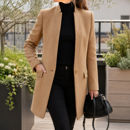 A woman wears a beige mandarin collar coat with a raised collar, single button front and flap pockets.