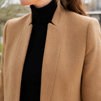 Close view of a beige mandarin collar coat showing raised collar, tailored shoulders and clean front edge.