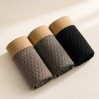 Three rolled boxer briefs in taupe, gray and black with tan elastic waistbands.