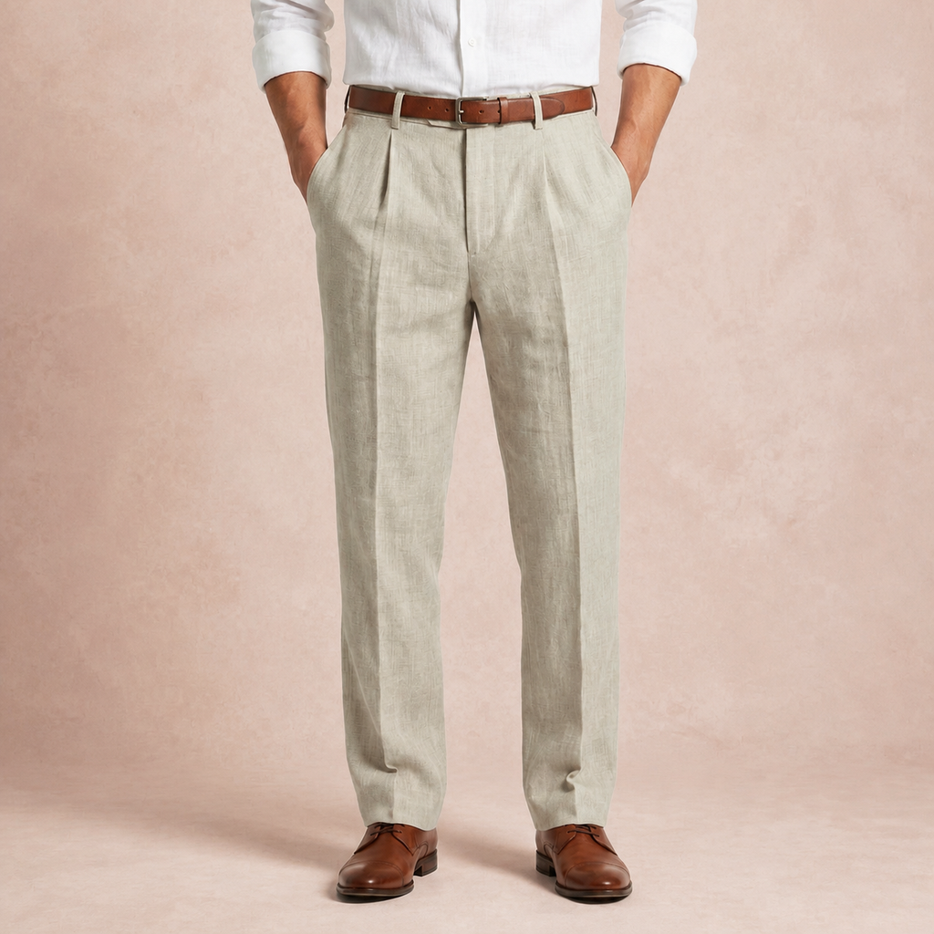 Beige full length linen trousers worn with white shirt, brown belt and brown shoes, hands in pockets