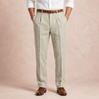 Beige full length linen trousers worn with white shirt, brown belt and brown shoes, hands in pockets