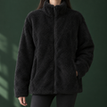 Woman wearing a black plush zip jacket with a stand collar and straight relaxed fit