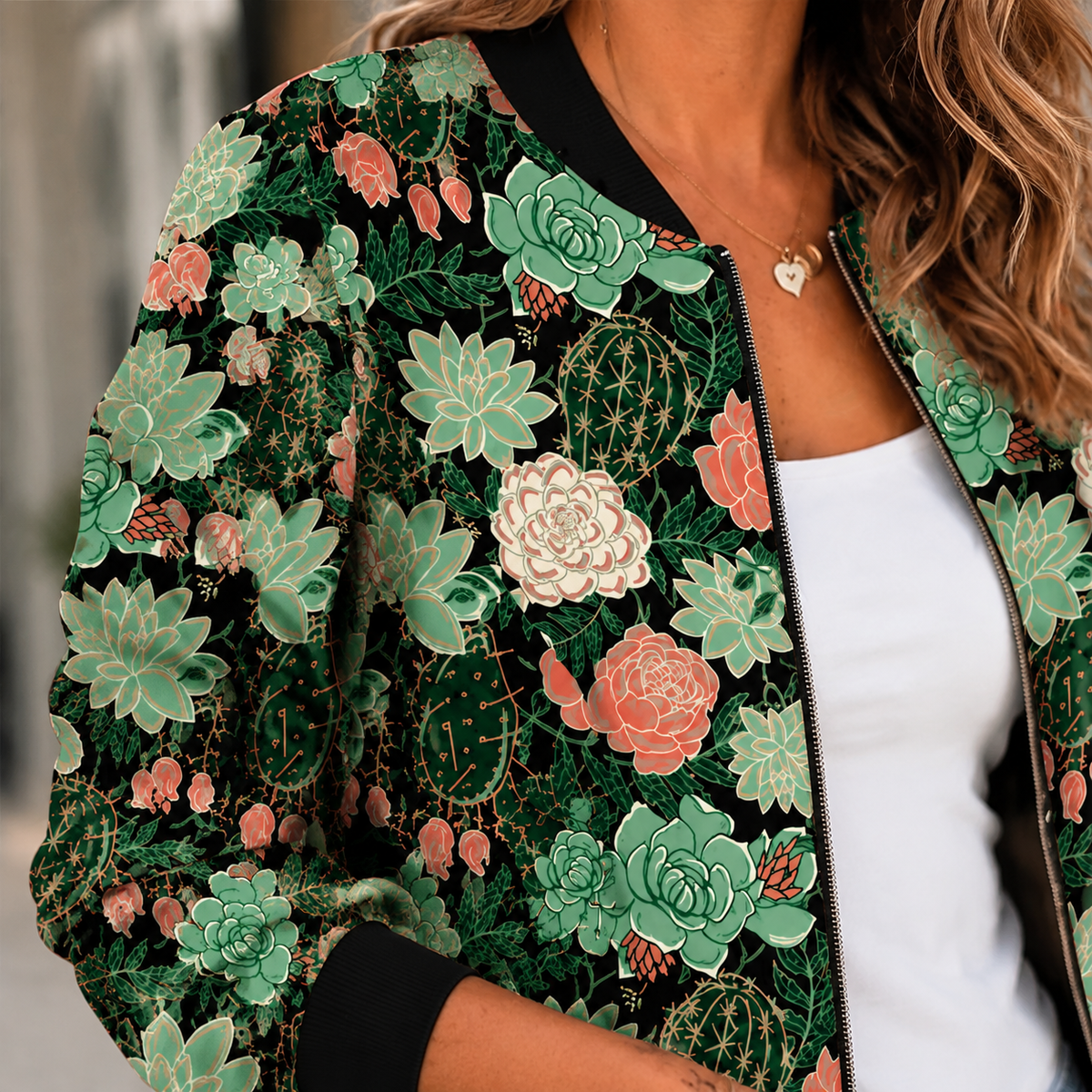 Close view of a green printed bomber jacket showing botanical print, front zipper and dark ribbed collar.