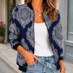 A woman wears a blue printed bomber jacket with a botanical pattern, front zip and ribbed trim.
