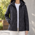 Woman wearing a black hooded jacket with a tonal leaf print and zip front