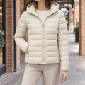 Woman wearing an apricot quilted hooded jacket with a slim silhouette and full front zip