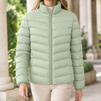 A woman wears a matcha green quilted puffer jacket with chevron quilting, a stand collar and front zip.