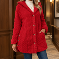 Woman wearing a red thigh length jacket with a plush raised texture and soft hood