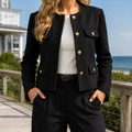 Black cropped blazer with gold-tone buttons and flap pockets worn over a white top.