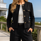 Black cropped blazer with gold-tone buttons and flap pockets worn over a white top.