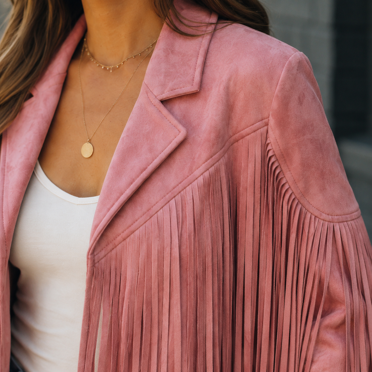 Close view of the pink fringe jacket showing the lapel and flowing sleeve trim.