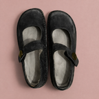 Black Mary Jane shoes with cross straps and round buttons, viewed from above.