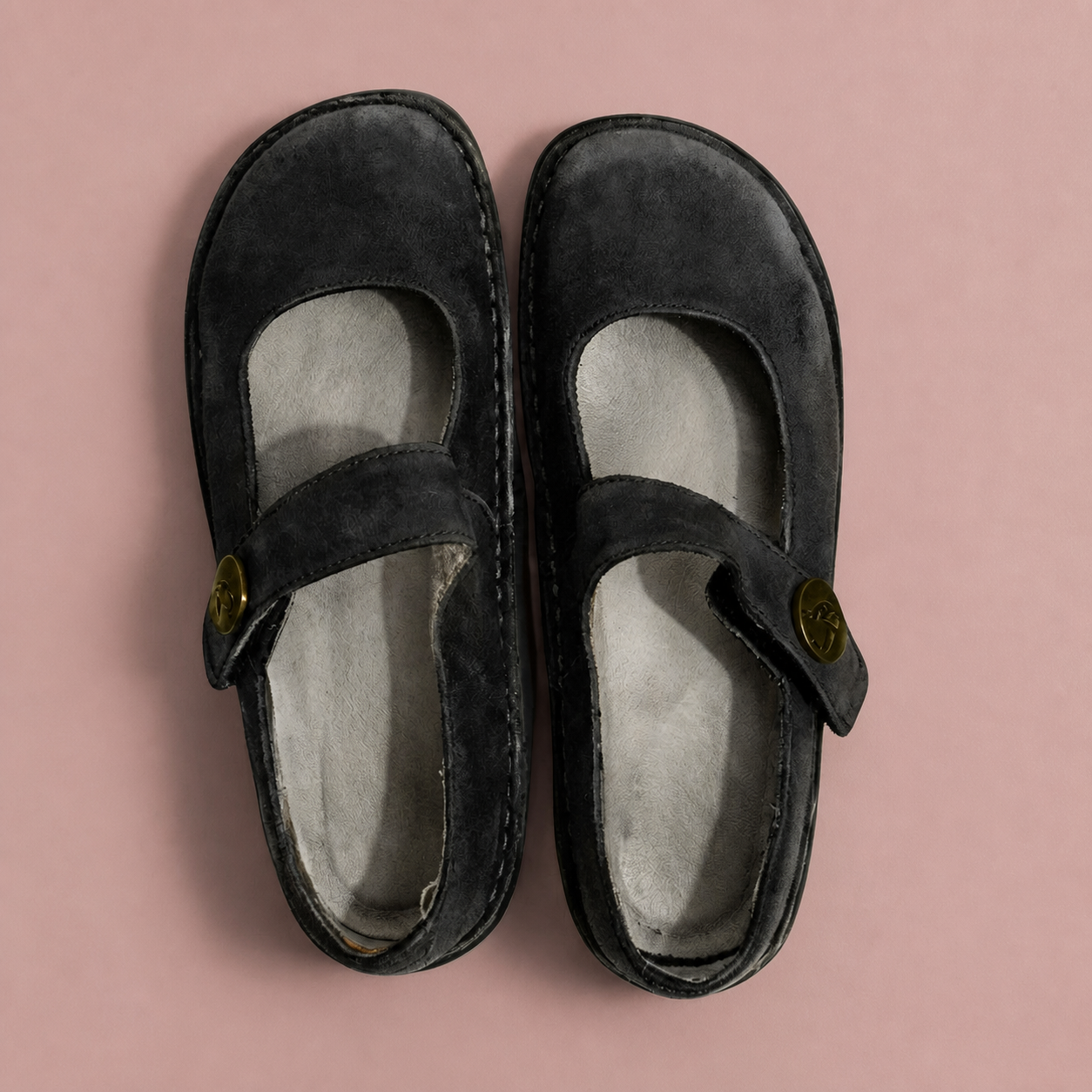Black Mary Jane shoes with cross straps and round buttons, viewed from above.