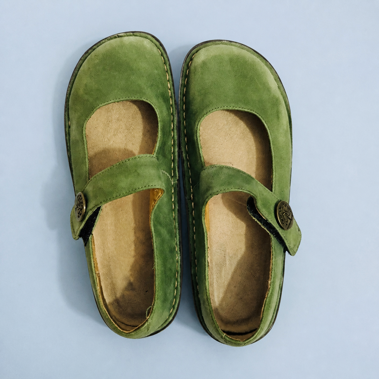 Green Mary Jane shoes with cross straps, viewed from above.