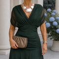 Green draped dress with a crossover neckline and sheer short sleeves.