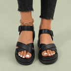 Black sandals with crossover straps and ankle buckles.