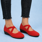 Red suede flats on feet under cropped black jeans