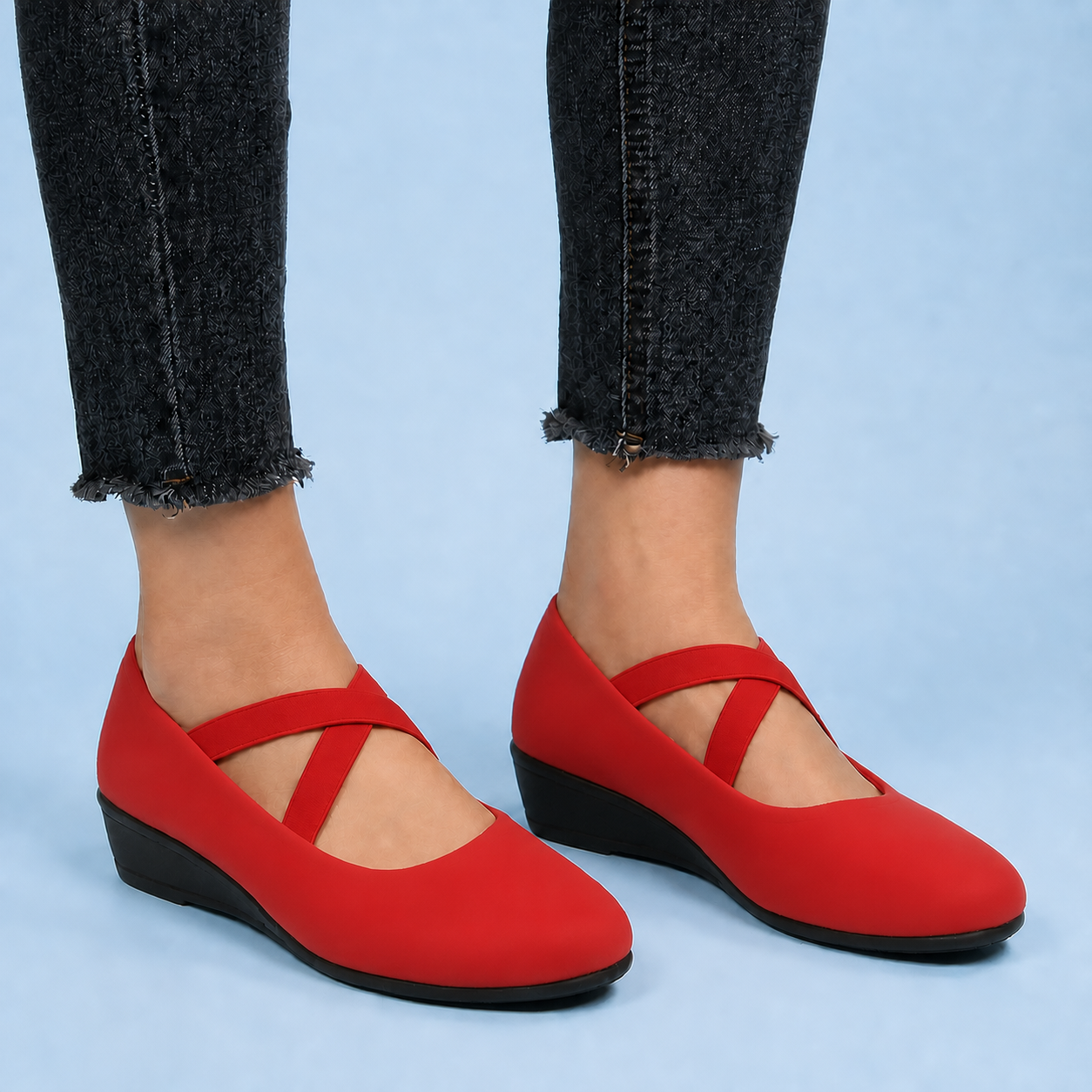 Red suede flats on feet under cropped black jeans