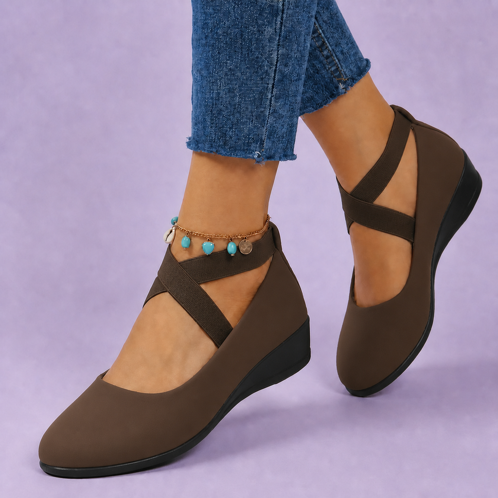 Brown suede flats on feet with crossed blue-jean legs and turquoise bead anklet