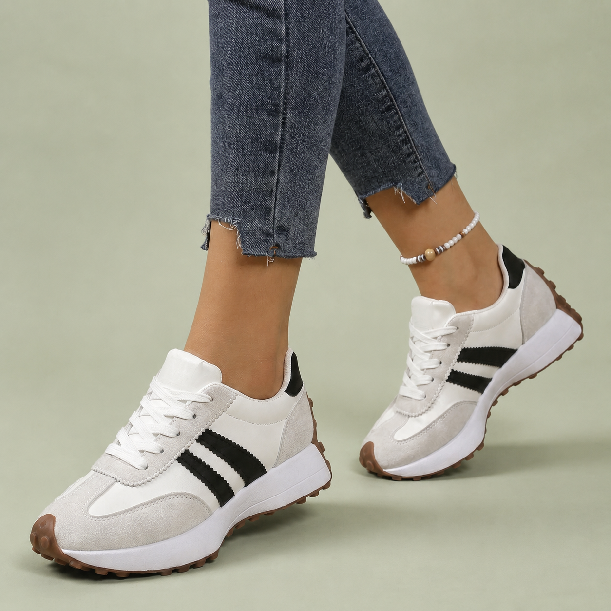 White sneakers with black side stripes and gum soles, worn with cropped jeans.