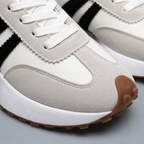 White sneakers showing suede toe panels, stitching and laces close up.