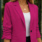 Close view of the pink blazer showing its notched lapel and gathered sleeves.