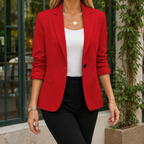 Red tailored blazer with ruched sleeves worn over a white top.