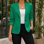 Green tailored blazer with ruched sleeves worn over a white top.