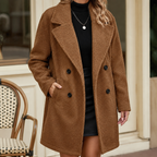A woman wears a brown wool blend coat with a teddy textured surface, broad lapels and double breasted buttons.