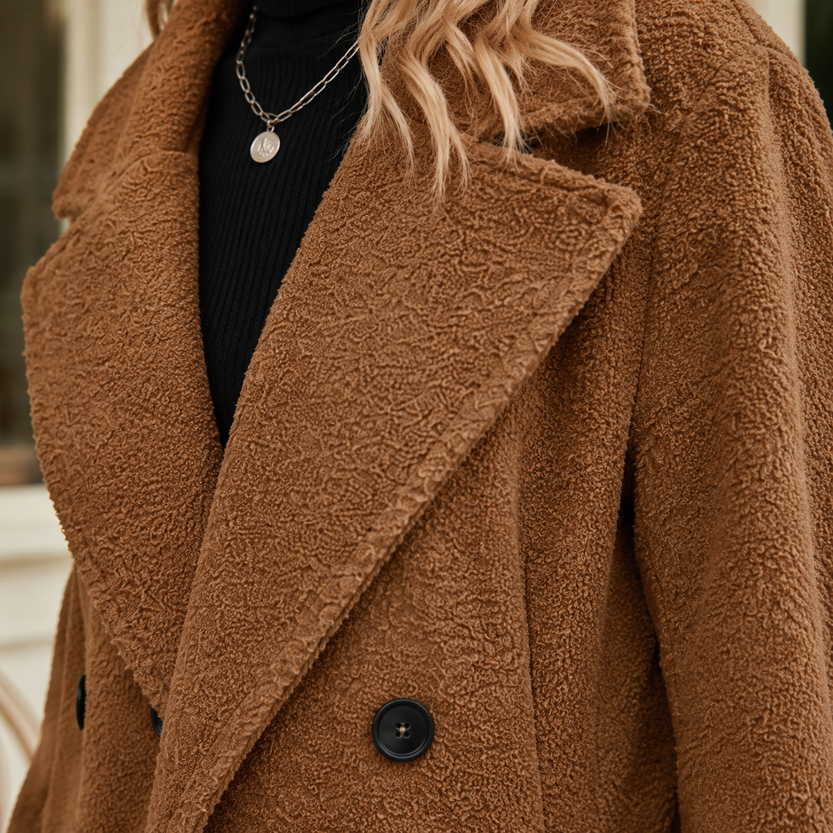 Close view of a brown wool blend coat showing teddy texture, broad notch lapels and dark buttons.